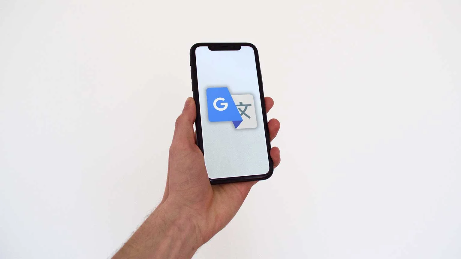 A hand holds a smartphone with the logo of Google Translate on the screen.