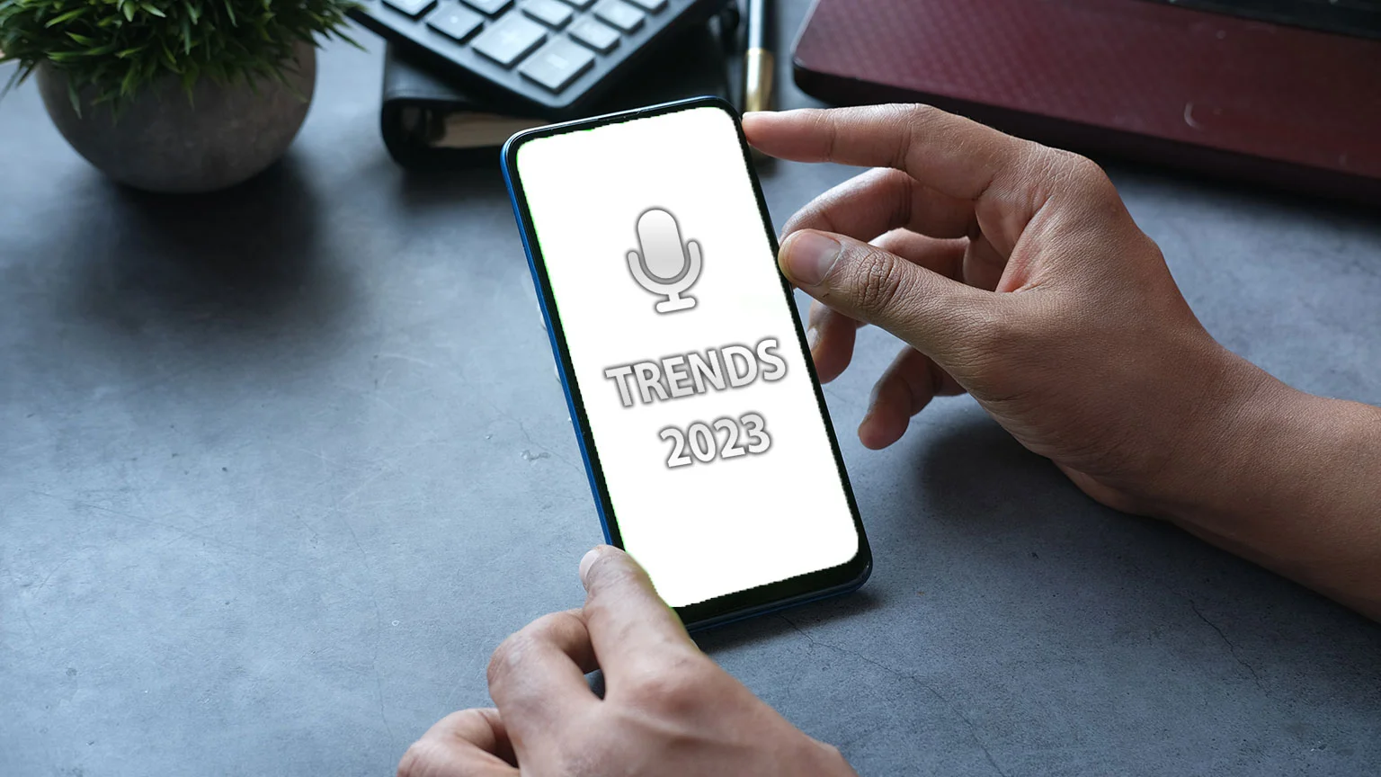Hands hold translation device with a microphone and the words Trend 2023 displayed on its screen.
