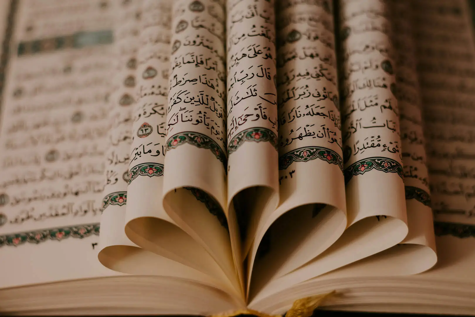 Seiten eines aufgeschlagenen Korans, die wie ein Fächer ausgelegt sind.
